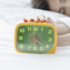 Woman with hand on alarm clock